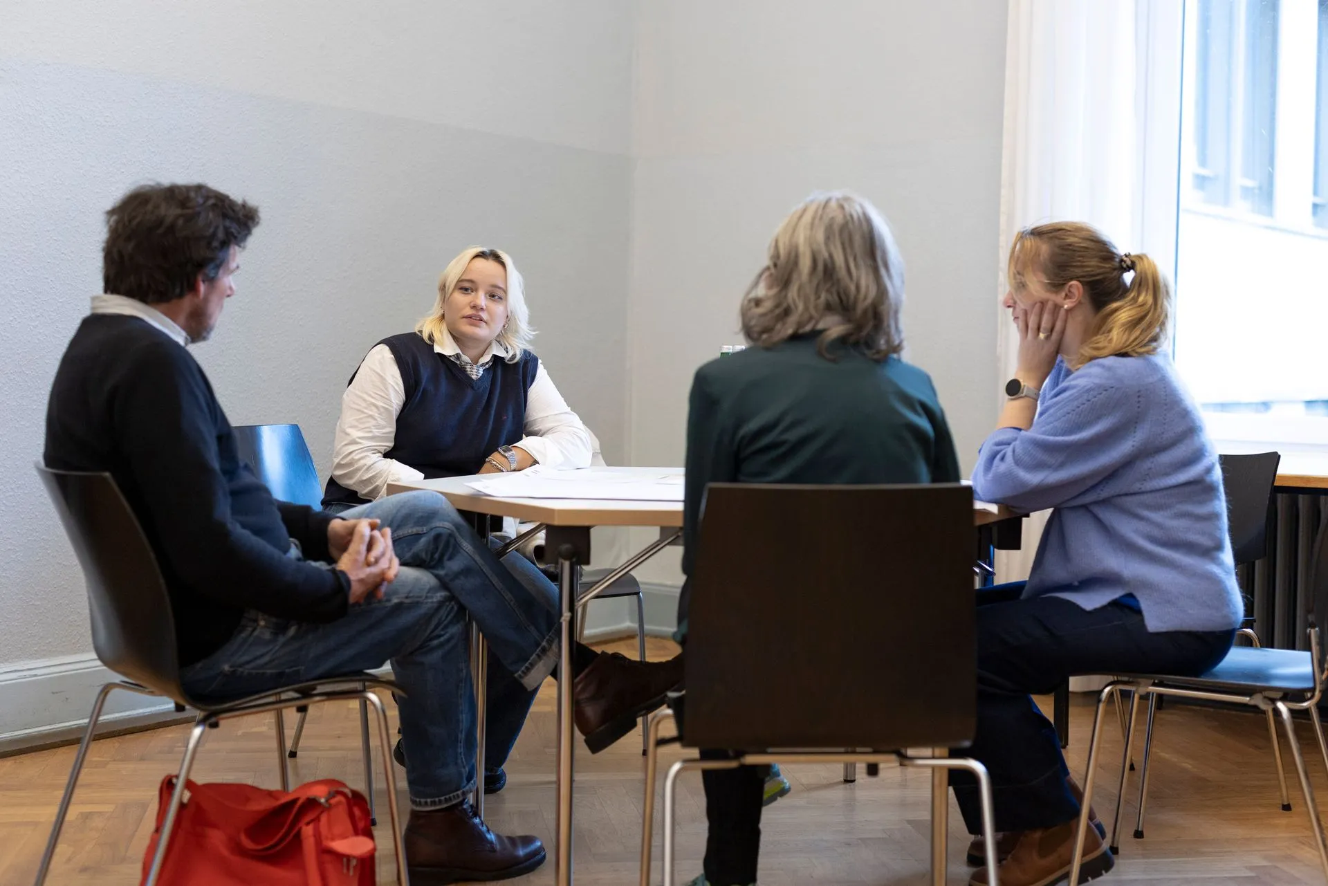 Vier Menschen sitzen an einem Tisch und hören einander zu.